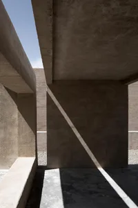 A modern interior featuring concrete columns and walls, with natural light coming through.