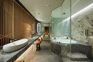 Modern bathroom with marble walls and a large soaking tub.