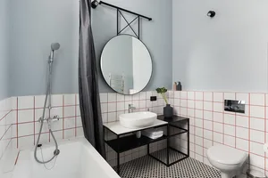 Modern minimalist bathroom featuring white and black tiled floor, white bathtub, and white sink with black faucet.