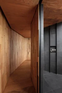 A modern minimalist bathroom with wooden paneling and dark gray tiles on the walls and floor.