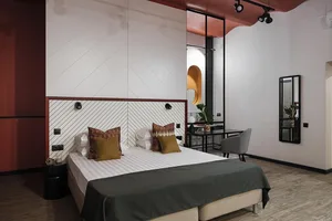 A minimalist bedroom with a white bed, taupe accents, and a minimalist design.