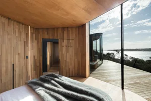 A modern residential interior with wooden walls and a view of the ocean.