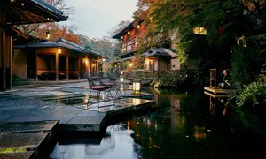 Outdoor seating area of a Japanese restaurant with natural stone floors, wooden railings, and lanterns.