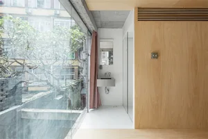 Modern minimalist bathroom with concrete flooring, glass shower enclosure, and wooden accents.