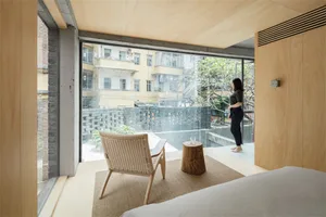 A minimalist bedroom featuring a large window with a view of the surroundings.