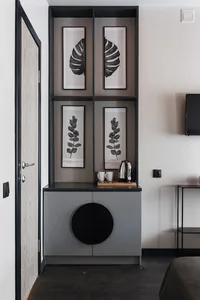 A minimalist residential coffee station with a metal shelf, black and white botanical prints, and a metallic kettle.
