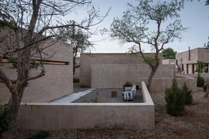 A minimalist residential patio with concrete walls and a modern outdoor sofa.