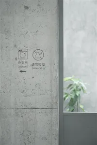 A minimalist concrete wall with signs for laundry and no smoking.
