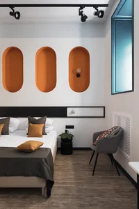 Modern bedroom with concrete walls, wooden floor, and fabric bedding and furniture.