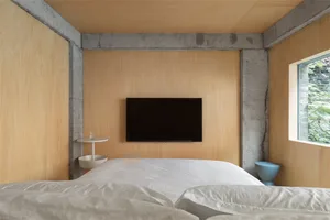 A modern bedroom featuring wooden-paneled walls and concrete columns.