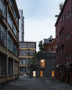 Modern black brick building in an urban setting with lights on.