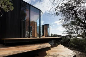 Modern house exterior with black wood paneling and a wooden terrace.