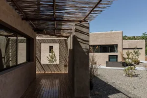 Modern house featuring concrete exteriors, wooden pergola, and landscaped courtyard.