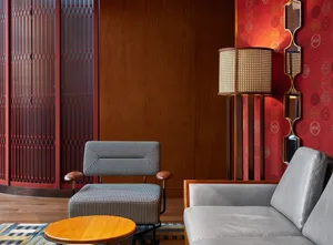 A modern living room featuring a gray sofa, a woven floor lamp, and a round wooden coffee table on a patterned rug.