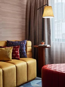 A modern living room featuring a yellow sofa, curtains, and a side table with a plant and books.