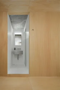 Modern minimalist bathroom with white walls, wooden walls and floor, and a concrete ceiling.
