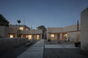 A modern residential house with concrete walls and a courtyard at dusk.