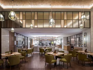 Dining and bar area of a modern restaurant with tables, chairs, and a service counter.