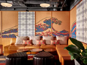 A contemporary retail interior featuring a custom wave pattern on fabric walls and a cozy seating area with plush pillows.