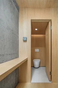 A modern bathroom with wood-paneled walls and a concrete floor.