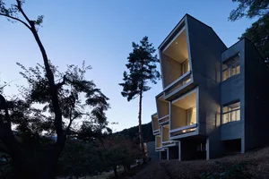 A modern residential building with concrete and glass exterior materials.
