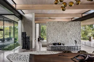 A modern living space with a concrete wall, wooden table, and black chairs, featuring a rugged texture and contemporary desig