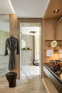 Modern bathroom features marble countertops, wooden accents, and a glass shower door.