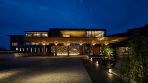 A modern resort entrance featuring a wooden canopy structure and concrete elements.