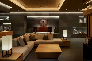 Contemporary living room with minimalist design, featuring wooden furniture, concrete walls, and metal accents.