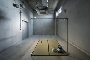 A minimalist industrial-style room with a metal-framed structure containing a tatami mat setup.