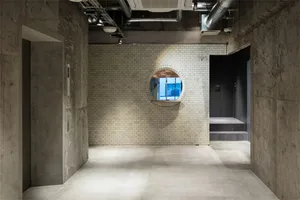 Industrial-style office lobby with concrete floors and walls, brick accent wall, and industrial-style lighting fixtures.