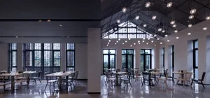 Modern industrial restaurant interior featuring metallic finishes, glass elements, and concrete surfaces.