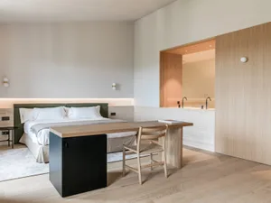 A minimalist bedroom with a bed, desk, and chair in a modern, clean design.