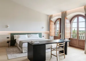 Modern, minimalist bedroom featuring a wooden bed, fabric bedding, and glass windows.