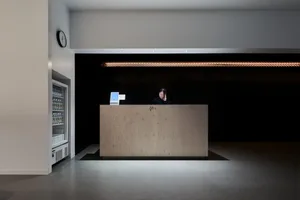 A minimalist reception desk with a wood finish located in a modern lobby setting.