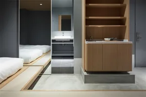 Modern minimalist residential room featuring a kitchenette with concrete and wooden elements.