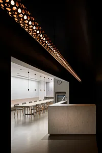 簡約餐廳室內，長形木桌搭配吊燈，以及接待櫃檯。