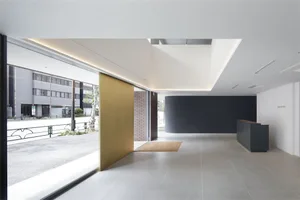 Modern hotel entry featuring gold accents, brick, concrete, and a black wall.