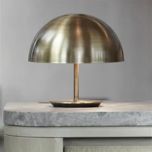A modern table lamp with a brass dome shade on a marble surface.