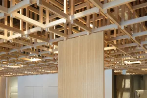 A modern interior space featuring a wooden grid ceiling and column.