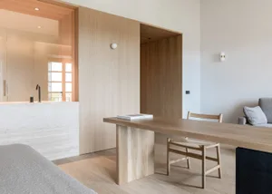 A modern living room with a wooden bench, chairs, and table.