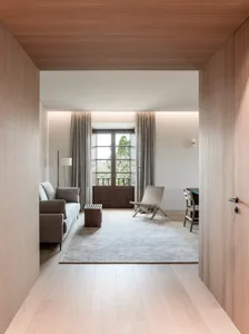 Contemporary living room with light wooden flooring, minimalist decor, and large windows letting in natural light.