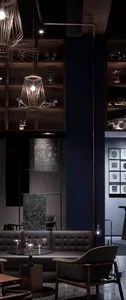 A modern restaurant bar setting with metal pendant lights, wooden shelves, and leather seating.