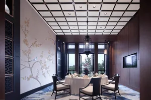 A modern restaurant interior with white walls, black ceiling, and black chairs around a round dining table.