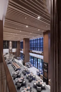 A spacious restaurant interior featuring modern design elements, including wooden accents and glass panels.