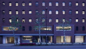 Brick building with illuminated windows and trees at dusk
