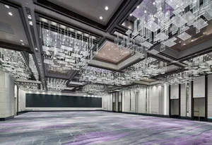 A spacious, industrial-style conference hall with metallic ceiling structures and a large, empty floor.