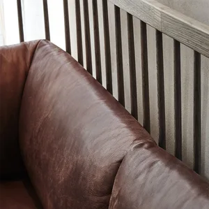Brown leather sofa with dark wooden slats in an industrial setting.