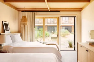 A minimalist bedroom featuring wood elements and a view of the beach outside.