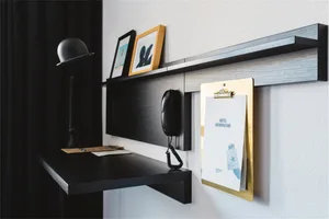 A minimalist hotel room desk with a black desk, black lamp, and a hanging hotel information clipboard.